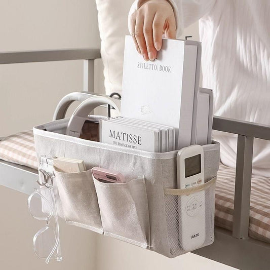 Gray hanging bed caddy with metal hooks, open multi-pocket storage for books