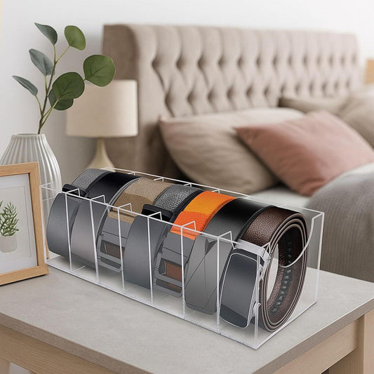 Clear acrylic belt organizer on a table with rolled belts and a tie