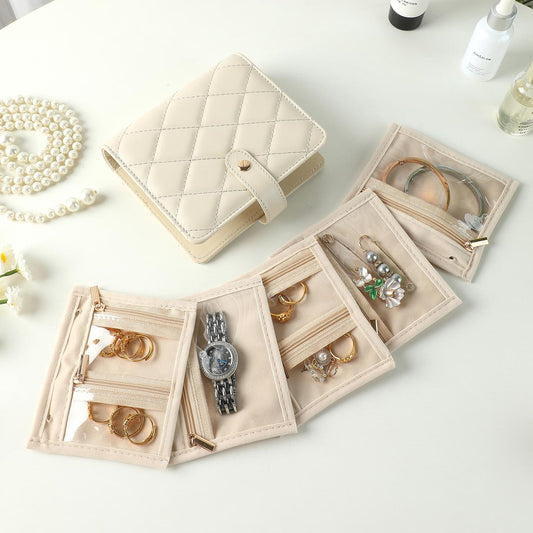 Jewelry organizer book opened with clear-window pouches and small ring compartments.