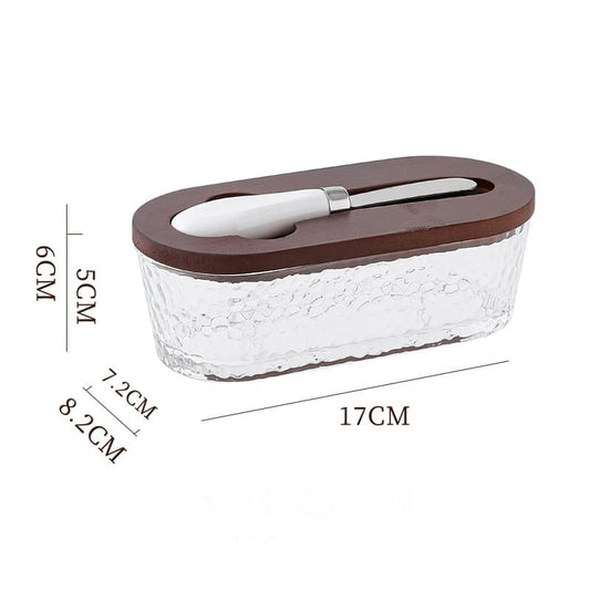 Glass butter dish with brown wooden lid and matching butter spreader