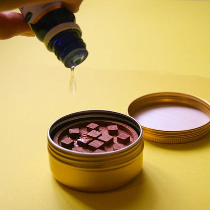 Open yellow diffuser container with wooden insert and small pink cubes inside