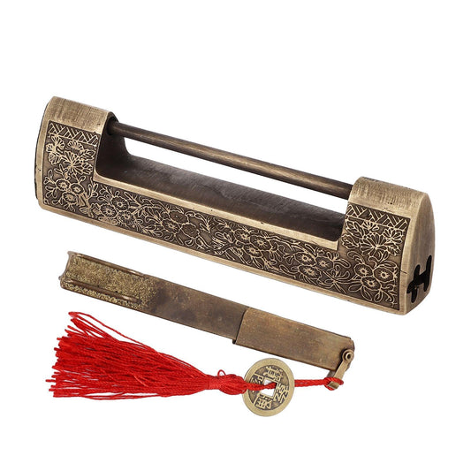 Antique brass horizontal padlock with floral scroll pattern, side view, with red tassel key.