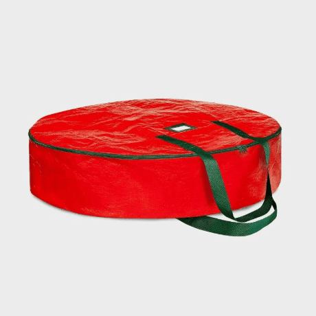 Red round wreath storage bag with green strap handle, closed top