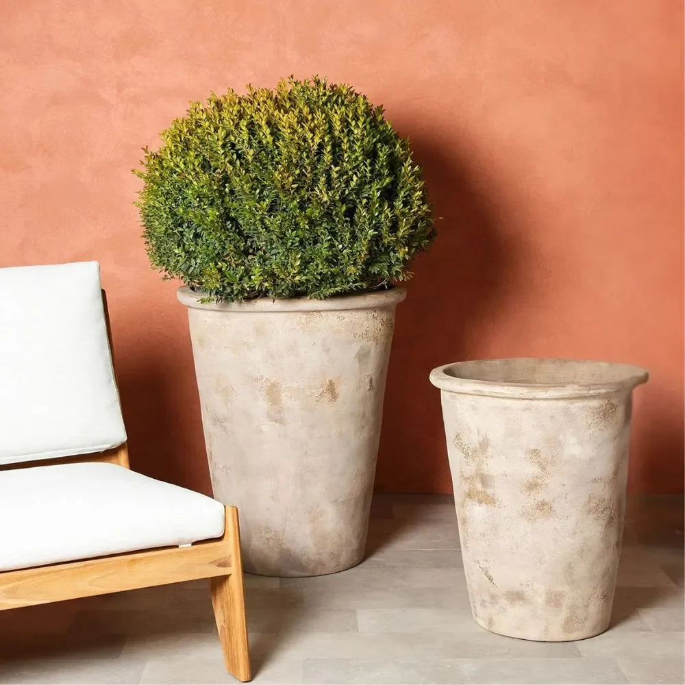 Conical planter pots with round topiary and cushion chair nearby