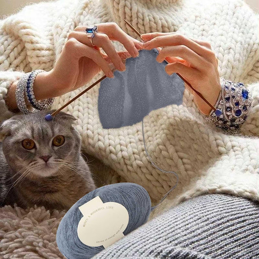 Blue mohair yarn ball with label near knitted blanket and cat