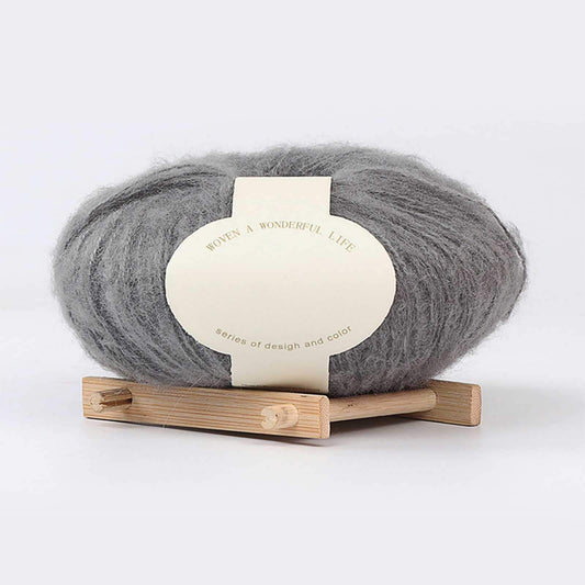 Grey mohair yarn skein on wooden stand with cream product label