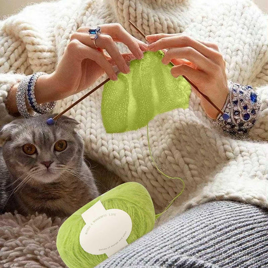 Green mohair yarn ball with label, shown with knitting hands
