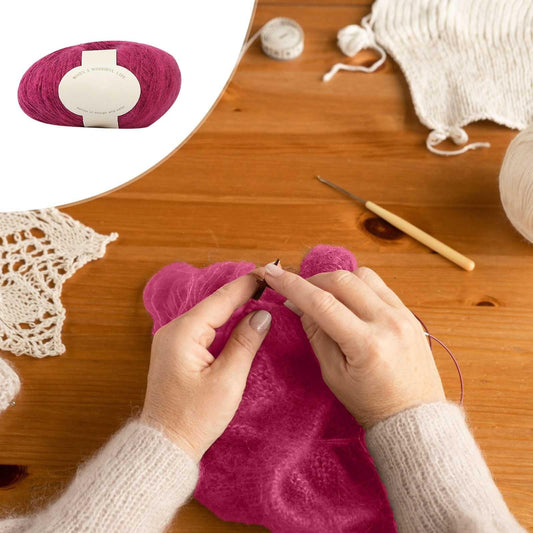 Magenta mohair yarn ball with cream label, hands winding yarn for crochet