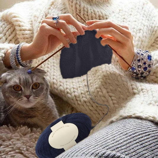 Navy mohair yarn skein with cream label, styled with knit fabric and crafting accessories