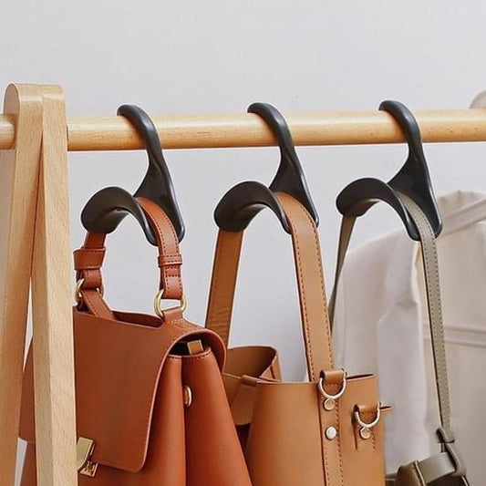 Tan and brown leather-look bag holders on a wooden bar with black hooks