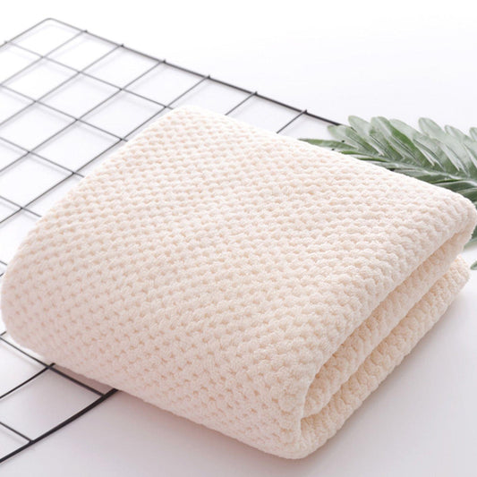 Beige bath towel roll, tightly folded with textured surface