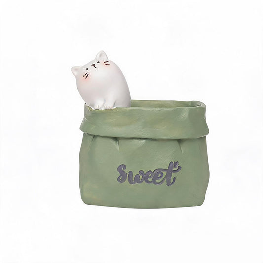 Paper-bag style pen holder with white cat figurine, green cup with Sweet print