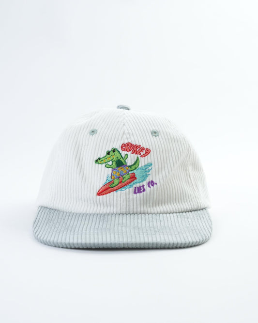 White ribbed baseball cap with embroidered green alligator logo and red text