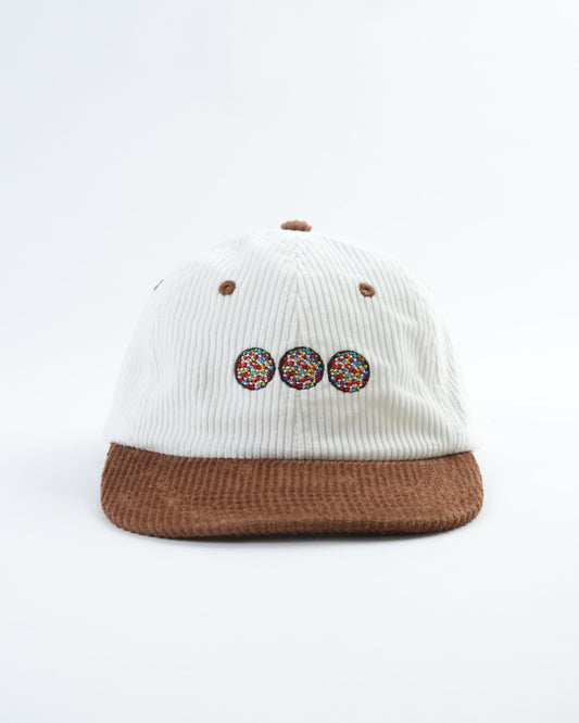 White ribbed cap with brown brim and three speckled chocolate badge patches