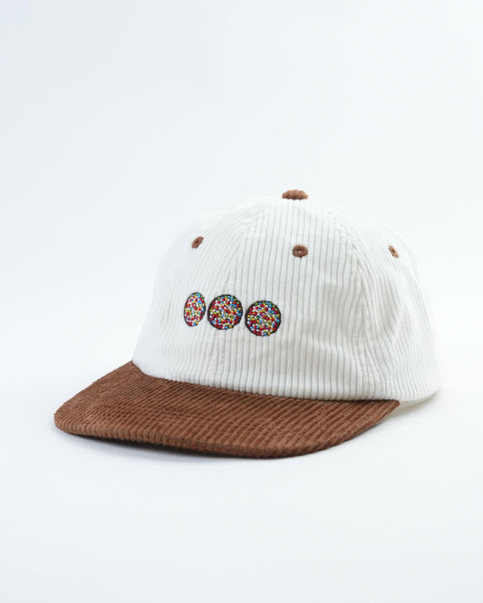 White ribbed baseball cap with brown brim and three chocolate freckle patches