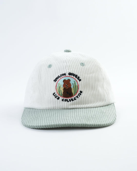 White ribbed baseball cap with embroidered quokka logo and light gray brim.