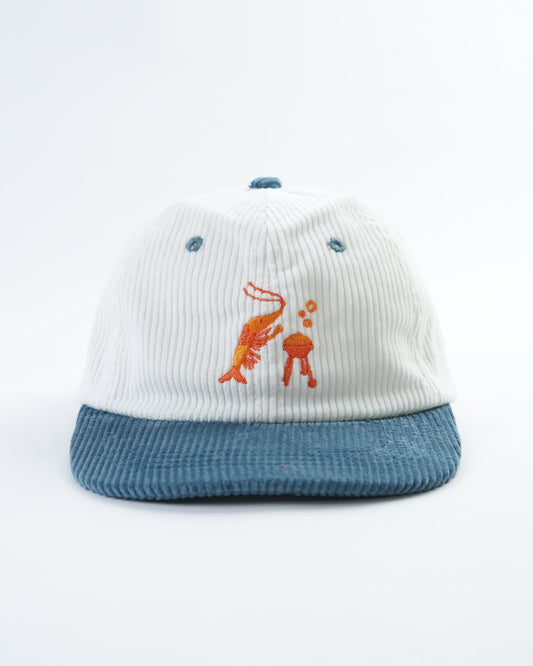 White ribbed baseball cap with blue brim and front embroidered shrimp and orange figure