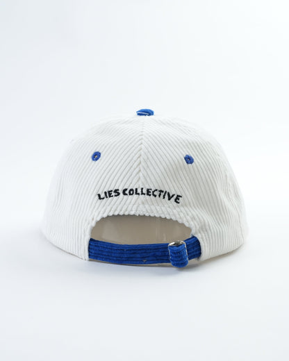 White cap with blue brim and 'LIES COLLECTIVE' embroidery