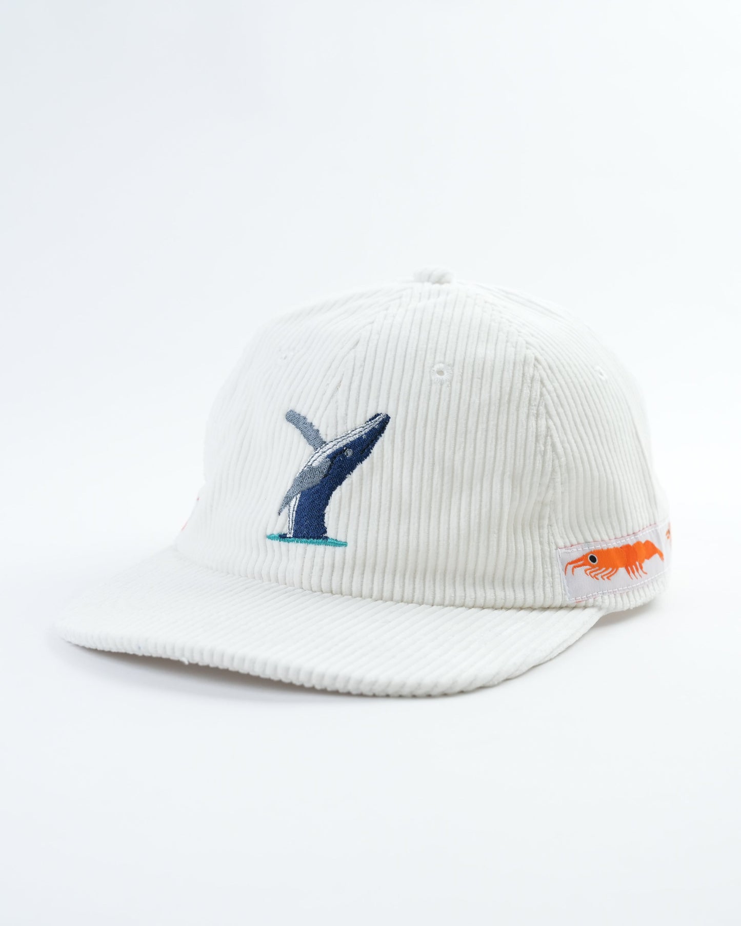 White cap angled view with embroidered whale graphic and orange fish side patch