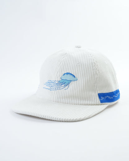 White ribbed baseball cap with blue jellyfish embroidery at center and blue side patch.