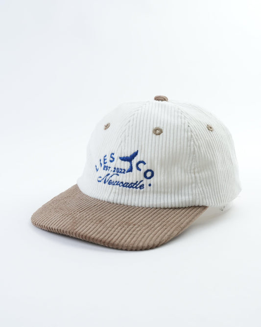 Two-tone baseball cap with blue embroidered logo on white ribbed crown and brown brim