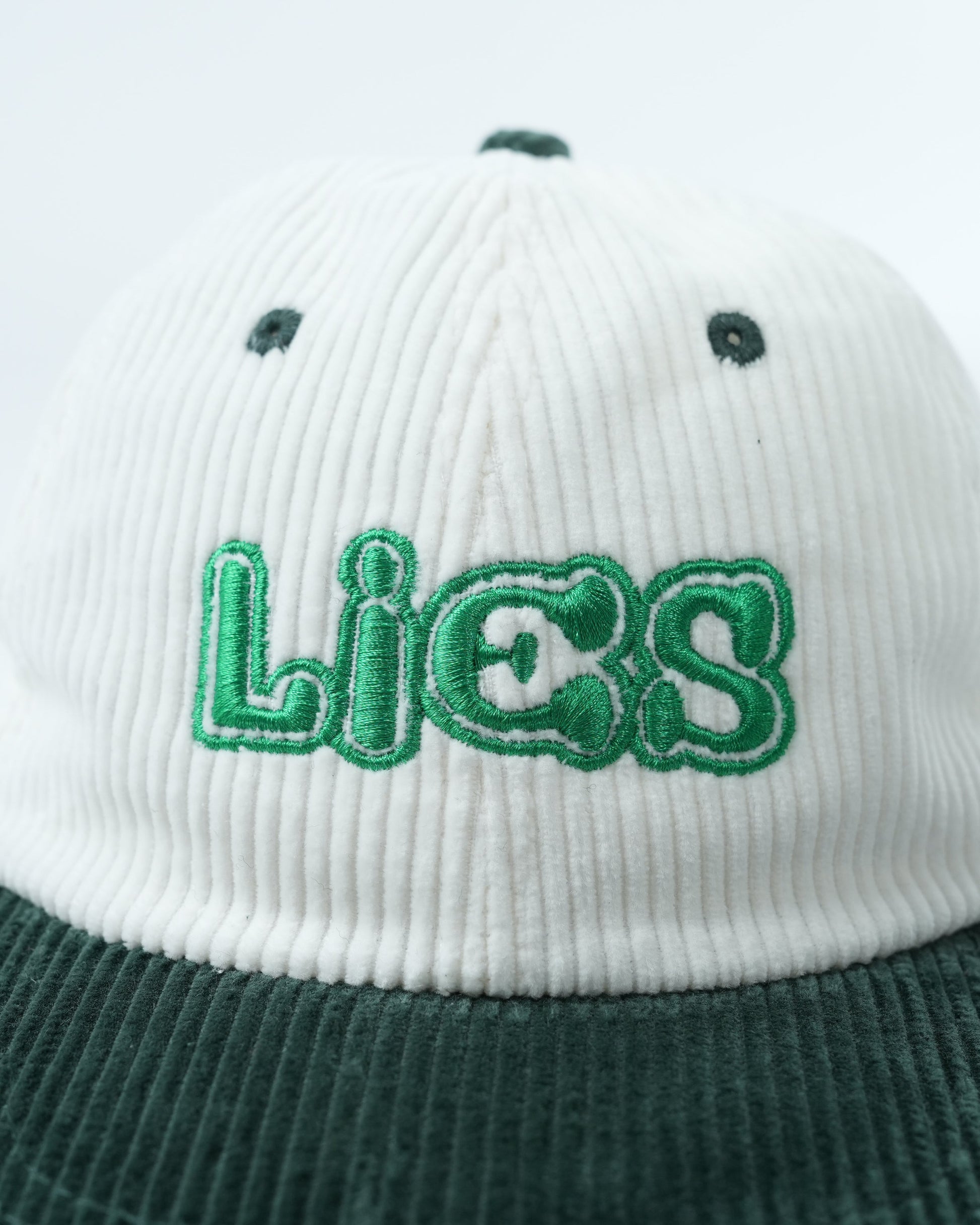 White ribbed cap with dark green brim and large green Lies logo back
