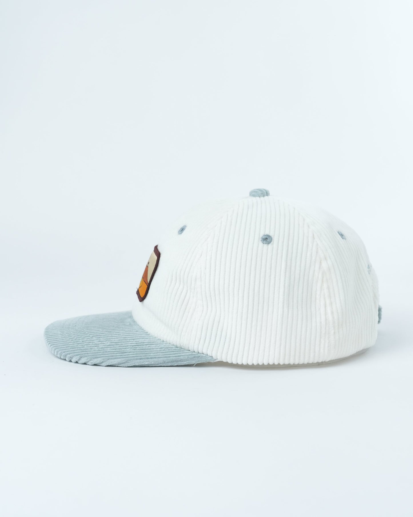 White corduroy baseball cap with light blue underside brim, side patch detail