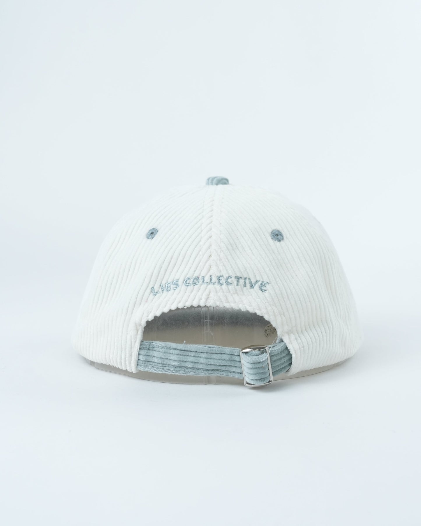 White corduroy baseball cap, interior view with striped lining and adjustable strap