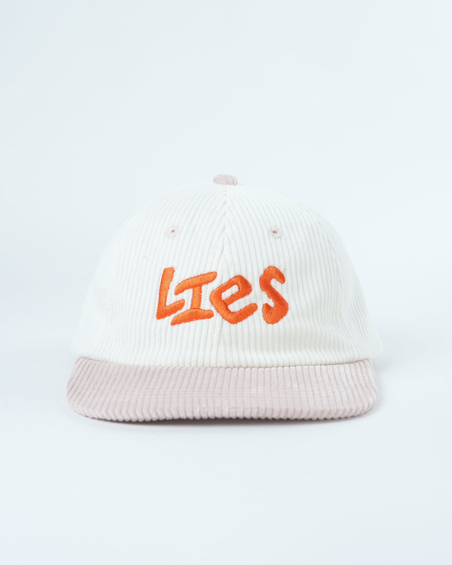 White ribbed knit cap with orange “Lies” logo and light pink striped brim