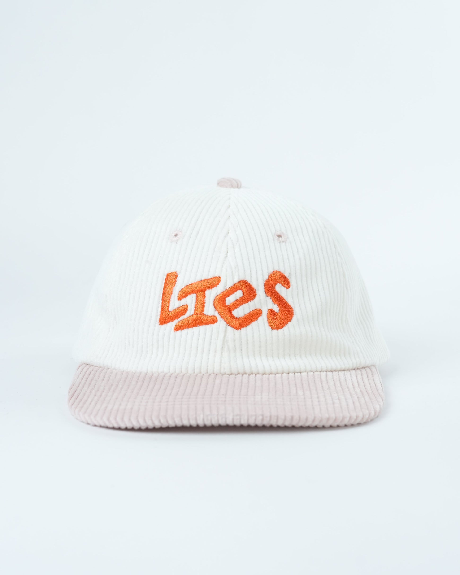 White ribbed knit cap with orange “Lies” logo and light pink striped brim