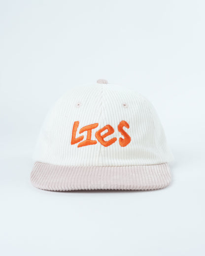 White ribbed knit cap with orange “Lies” logo and light pink striped brim
