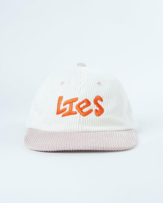 White ribbed knit cap with orange “Lies” logo and light pink striped brim