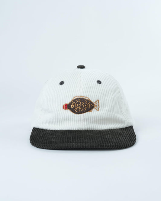 White ribbed baseball cap with dark brim, fish patch front and small dot accents