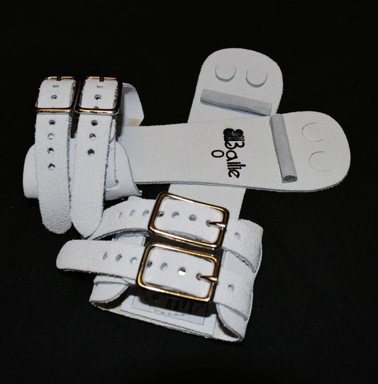 White dowel grip pair with crossed straps and gold buckle closures