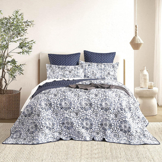 Quilted reversible coverlet set in white with navy circular pattern, on bed
