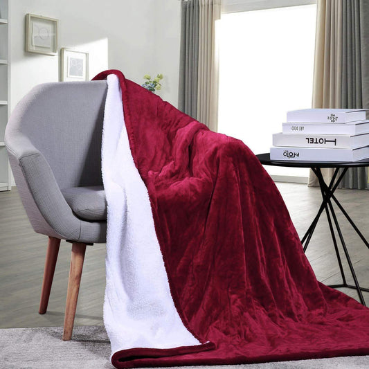 Heated electric throw blanket draped over chair, red fabric with white sherpa edge