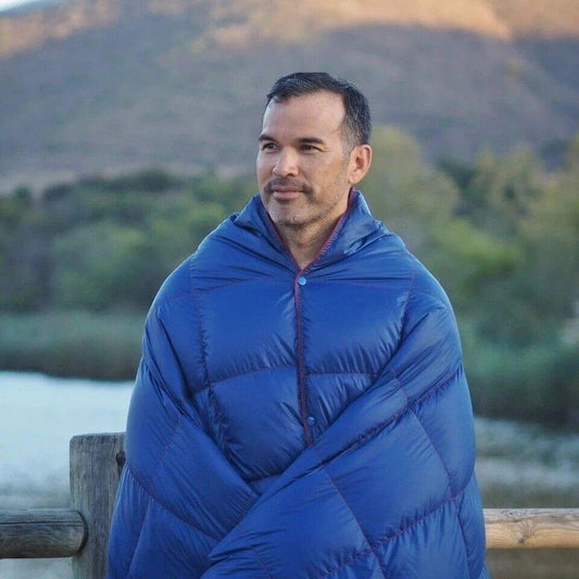 Wearable blue puffer blanket with hood and diagonal quilting, red button placket