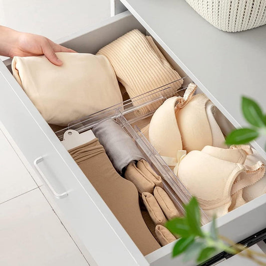 Transparent plastic drawer divider separating folded clothes in a drawer
