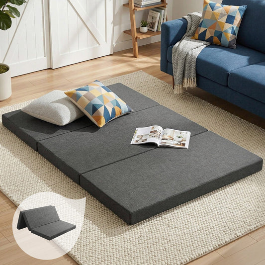 Foldable gray foam mattress on the floor with two folded sections and two pillows