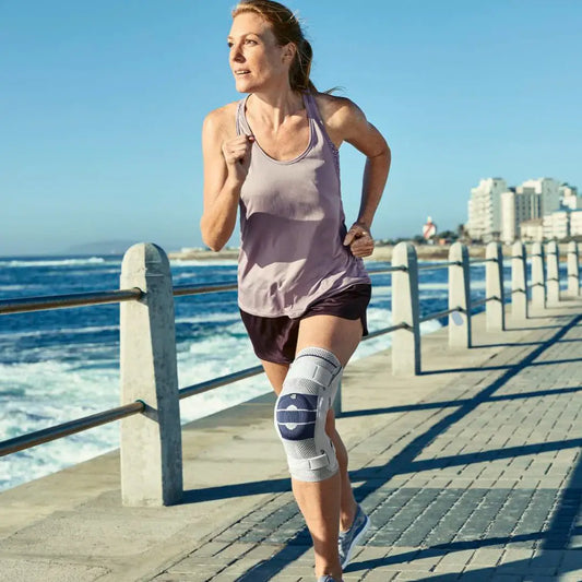 Hinged knee brace shown on a runner’s leg, with blue-striped support panels.