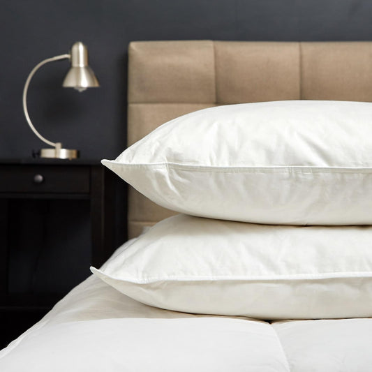 White goose-feather and down pillow on bed with light beige headboard
