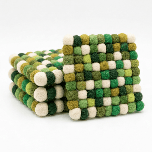 Set of round wool felt coasters with green, cream, and yellow pom-pom checker pattern