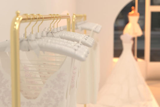 Set of white satin padded hangers on a gold rack, with bows and hooks