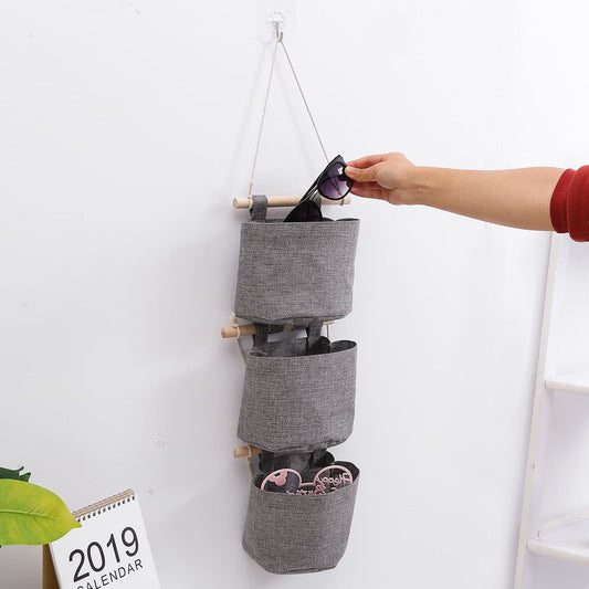 Gray over-the-door storage bag with three pockets and top hanging straps