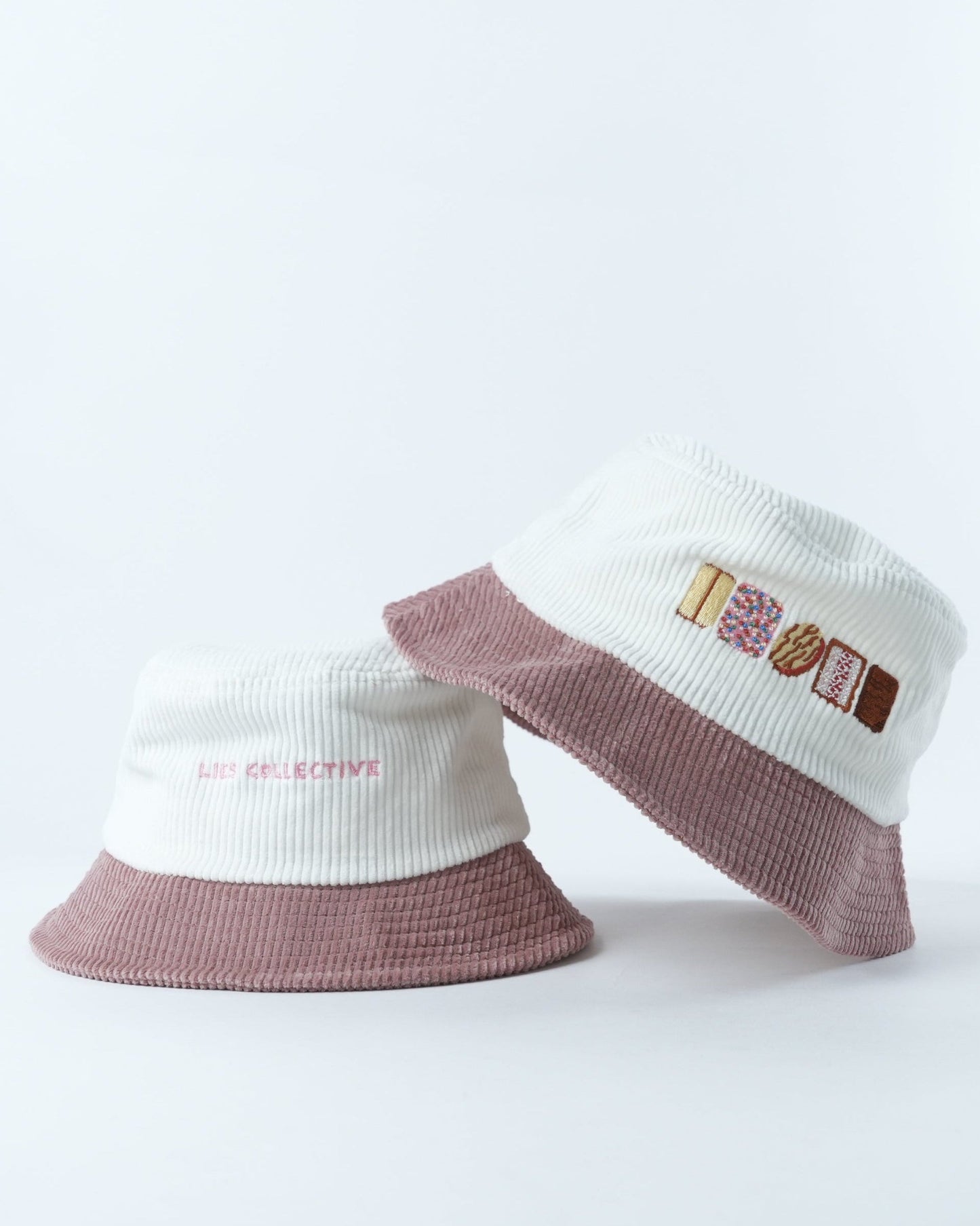 Bucket hat with white knit crown, mauve brim, and biscuit graphic front patch