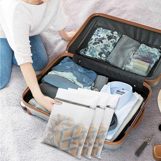 White mesh laundry wash bags with metal zipper, packed inside a suitcase for travel