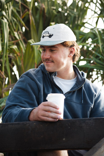 Troopy hat on head with white crown and teal brim, worn with casual hoodie.