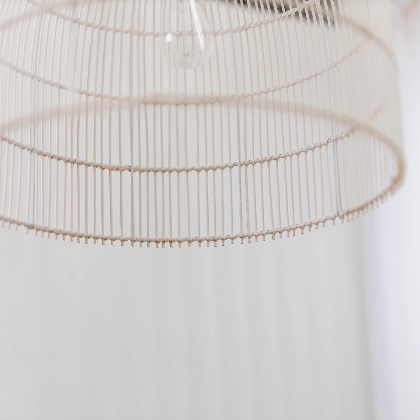 Close-up of whitewash rattan cane pendant shade with curved ribs and slatted lattice