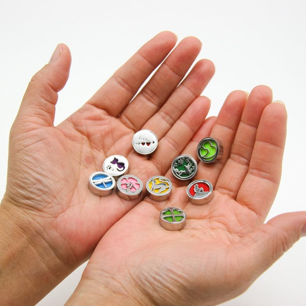 Set of round wearable diffuser lockets with different animal designs held in open hand