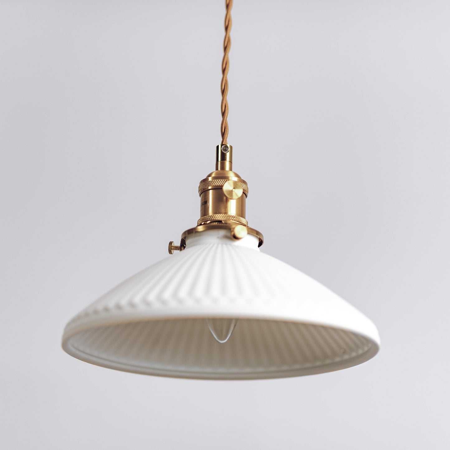 Ceramic pleated pendant light with wide white ribbed shade and brass top mount